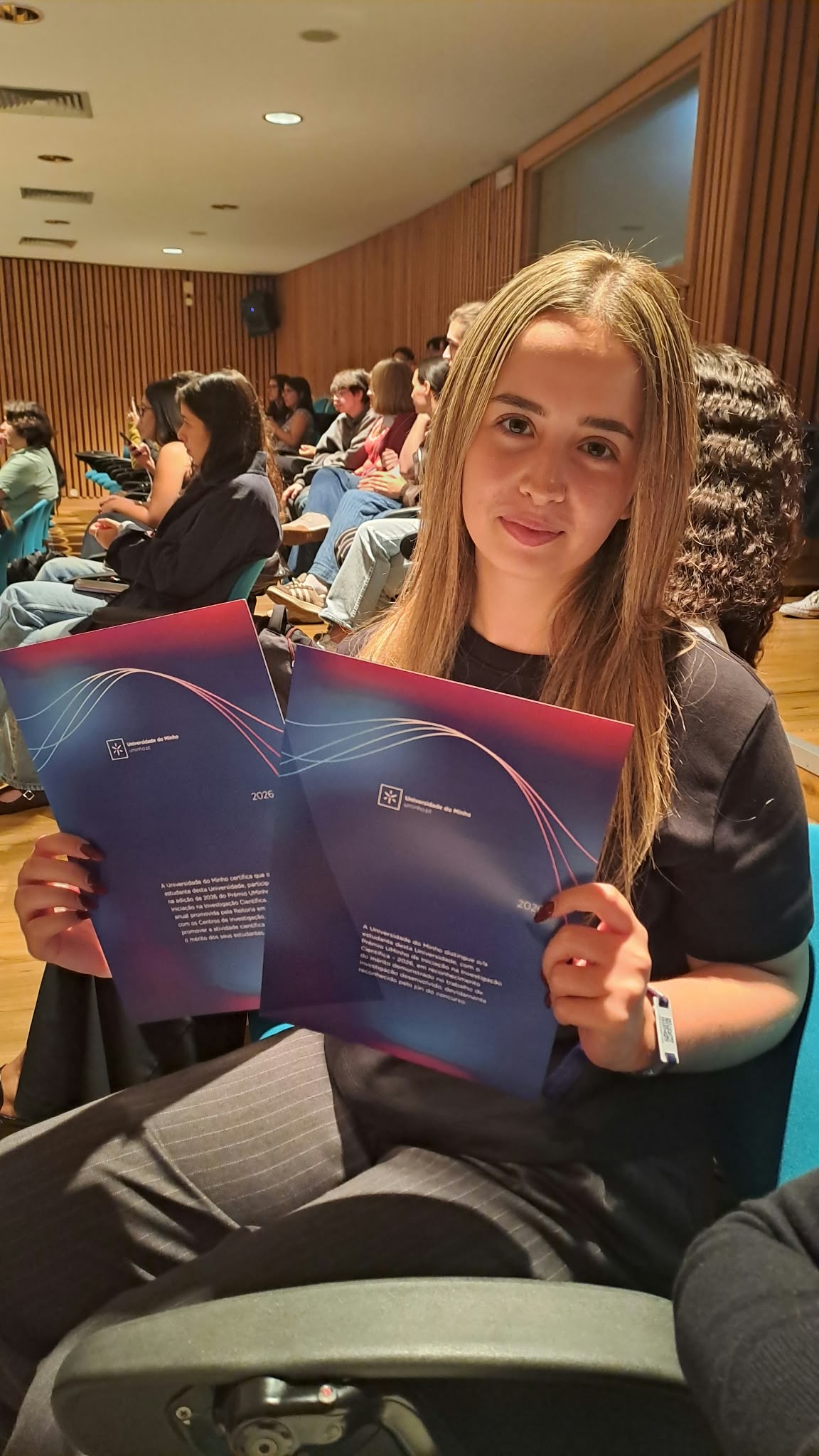 Filipa Veloso Rodrigues holding certificate folders at the UMinho ceremony