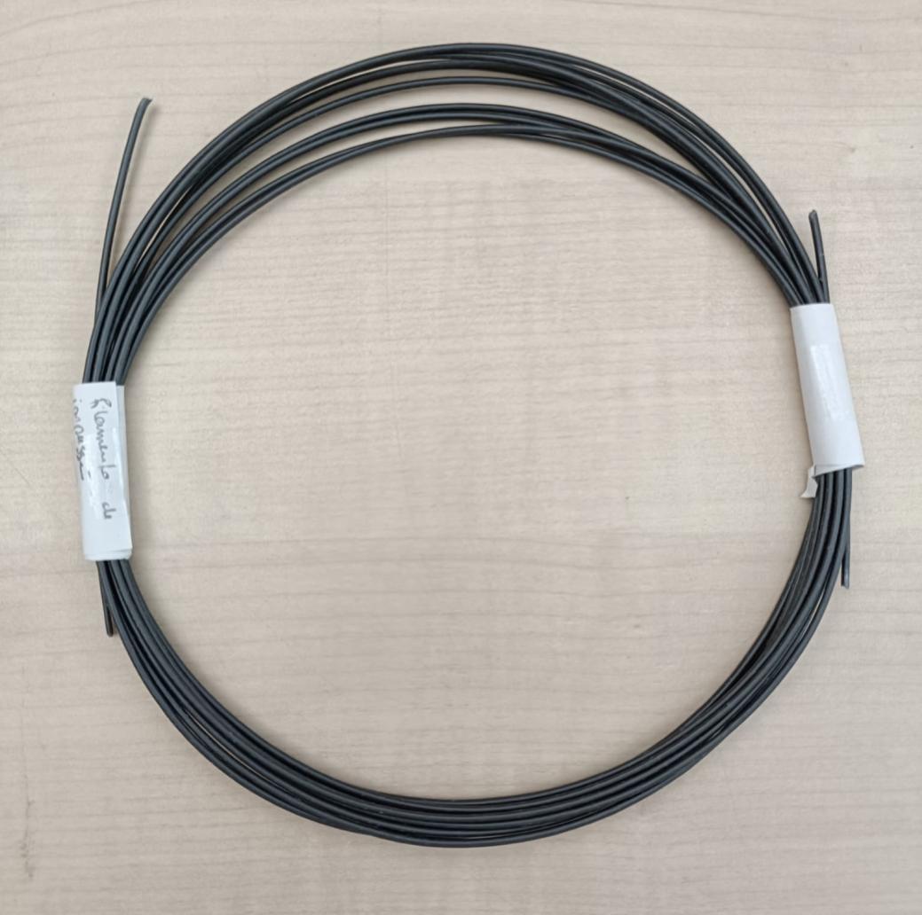 Original laboratory photograph of a coil of dark PHA–MXene filament on a workbench